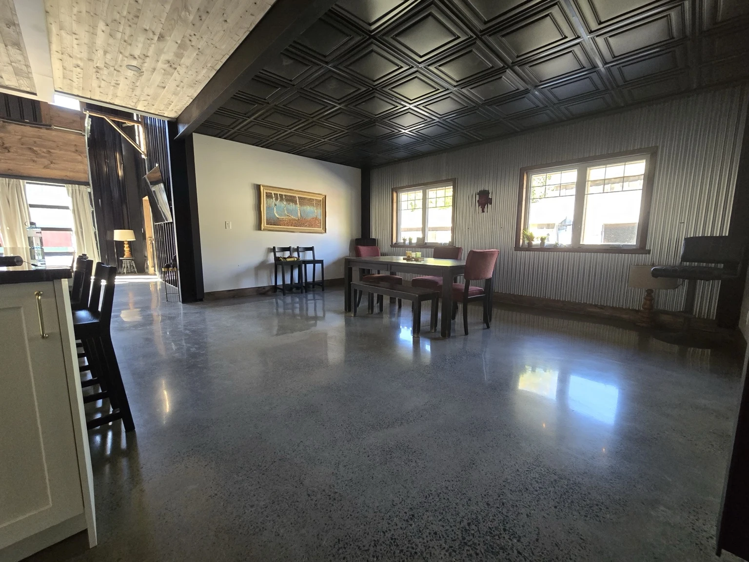 Open dining area with black ceiling tiles and polished concrete floor