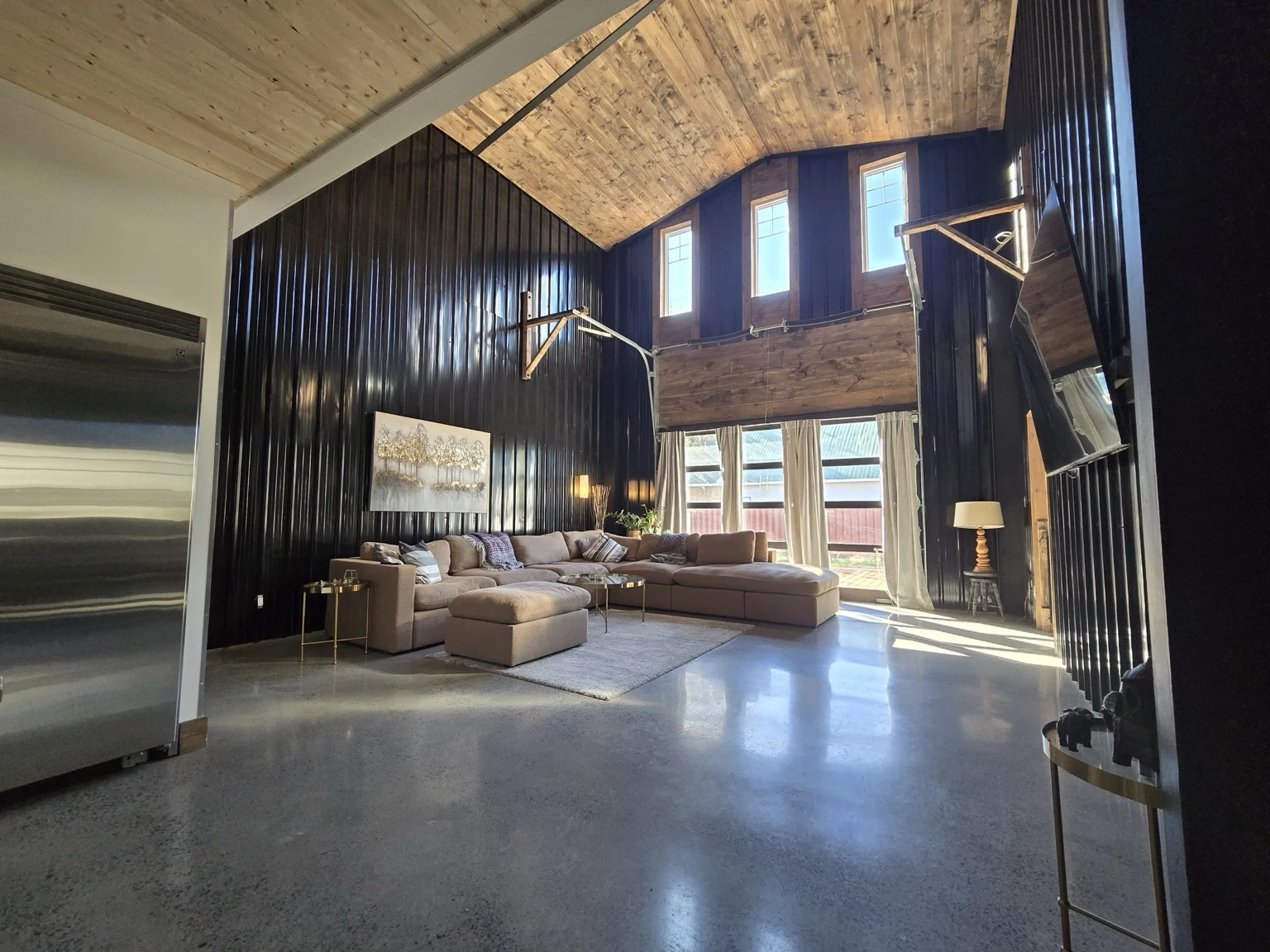 Vaulted living room with warm timber ceiling and black steel walls