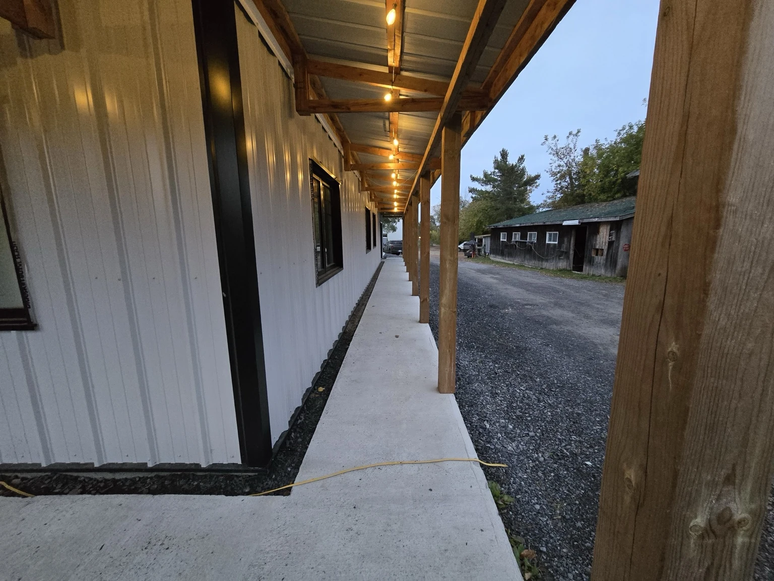 Timber posts and beams supporting a wraparound porch with warm lighting