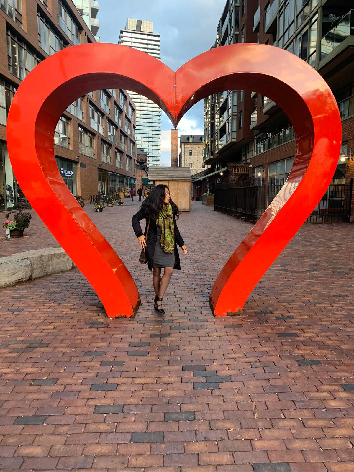 Criscilla beside a large red heart sculpture in Toronto