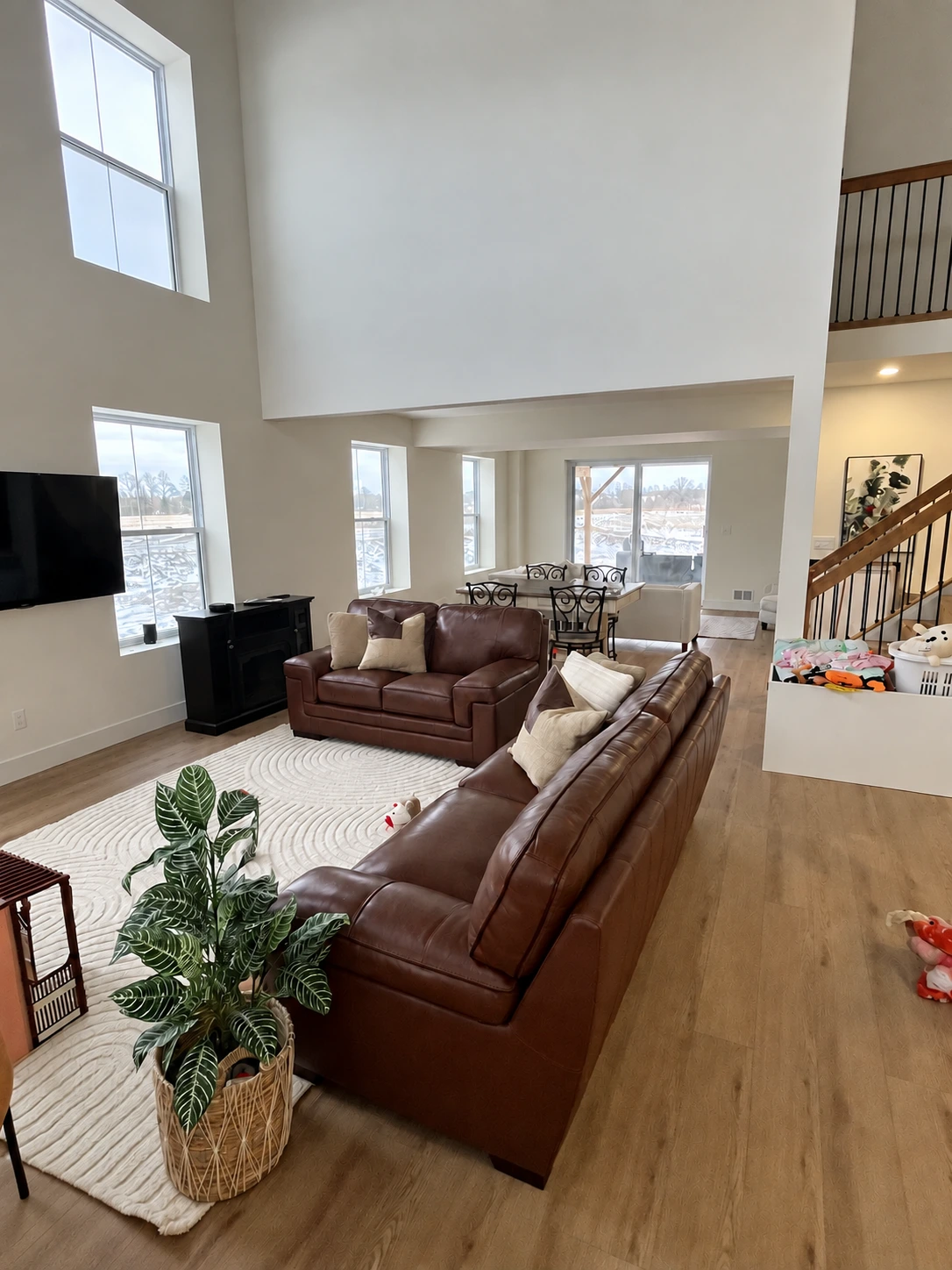 Mossley living and dining space with tall windows, a mezzanine and warm wood floors