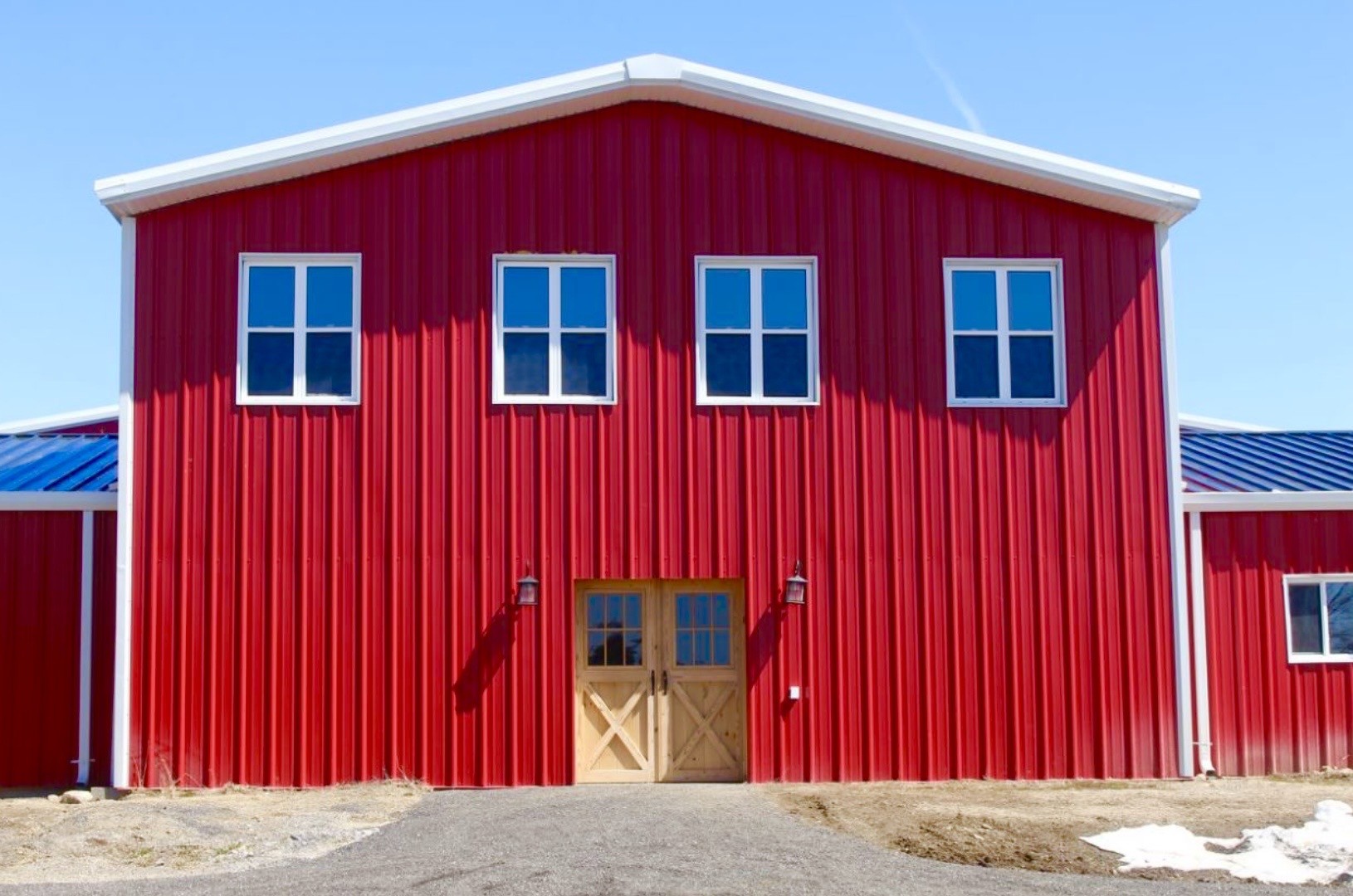 Red steel-clad building with white trim and timber entrance doors