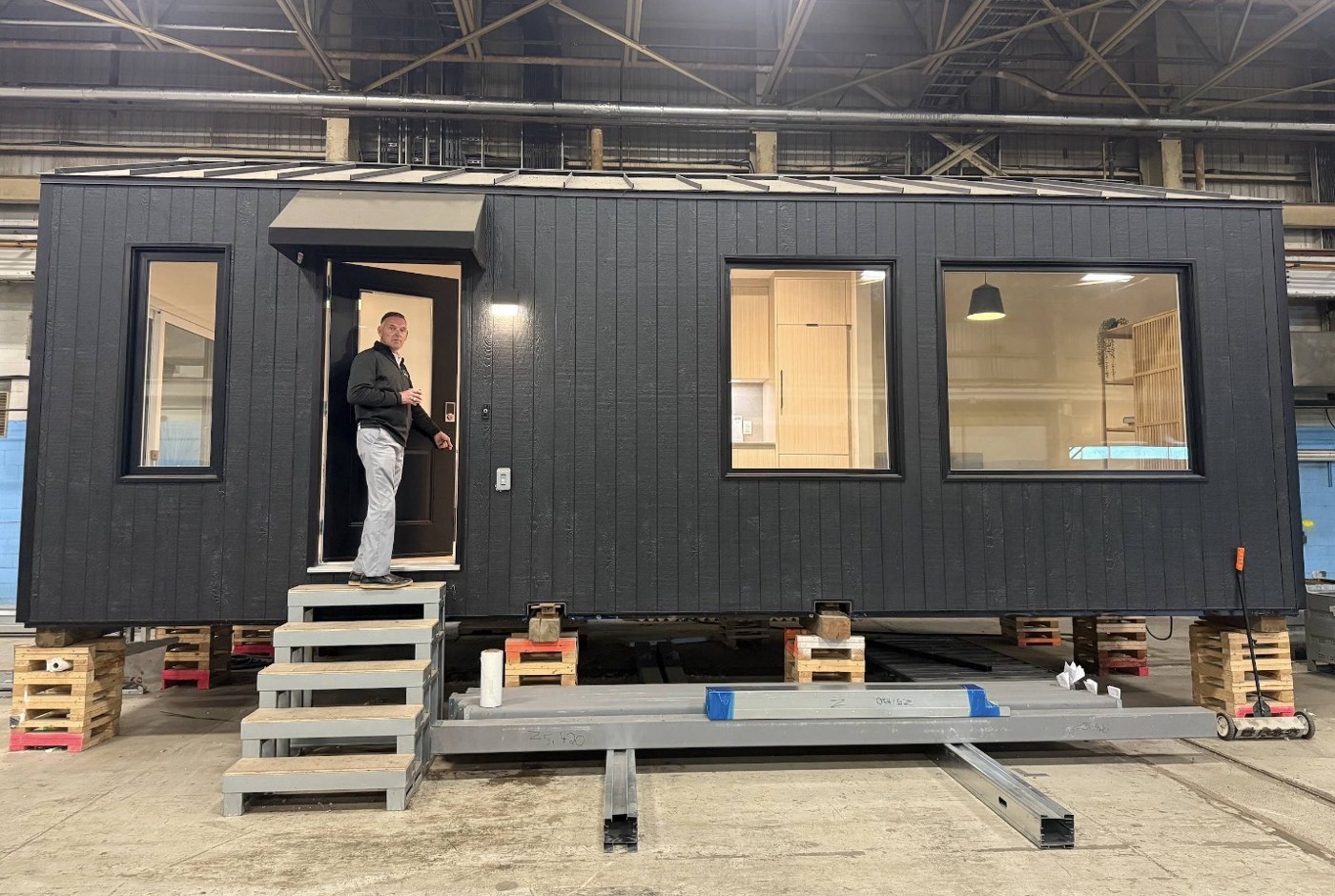 Compact dark-clad home inside a factory with access steps